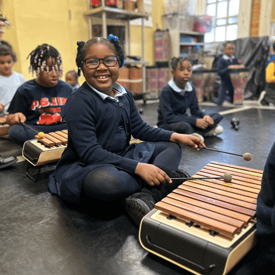 A girl in a class playing a guitar.
