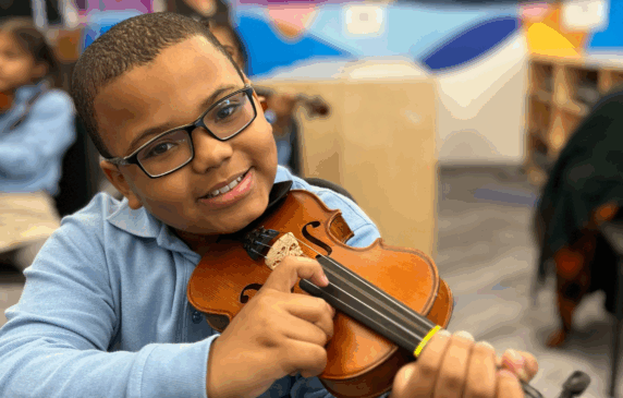 Young student playing a violin during a music lesson.