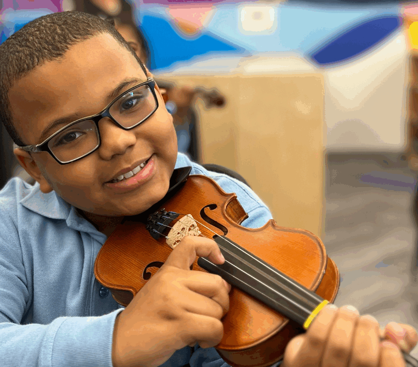 Young student playing a violin during a music lesson.
