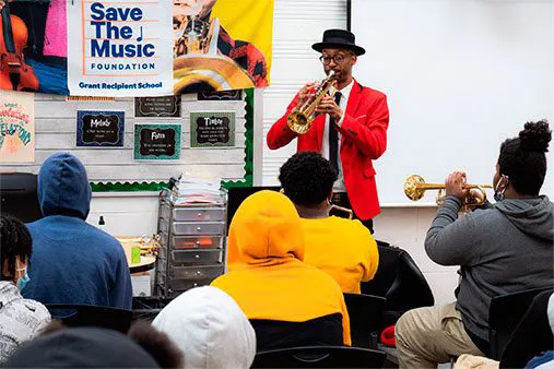 Teacher playing the trumpet in front of a group of students.